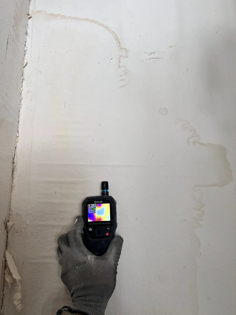Thermal meter held to a water-stained garage wall in an Aliante home