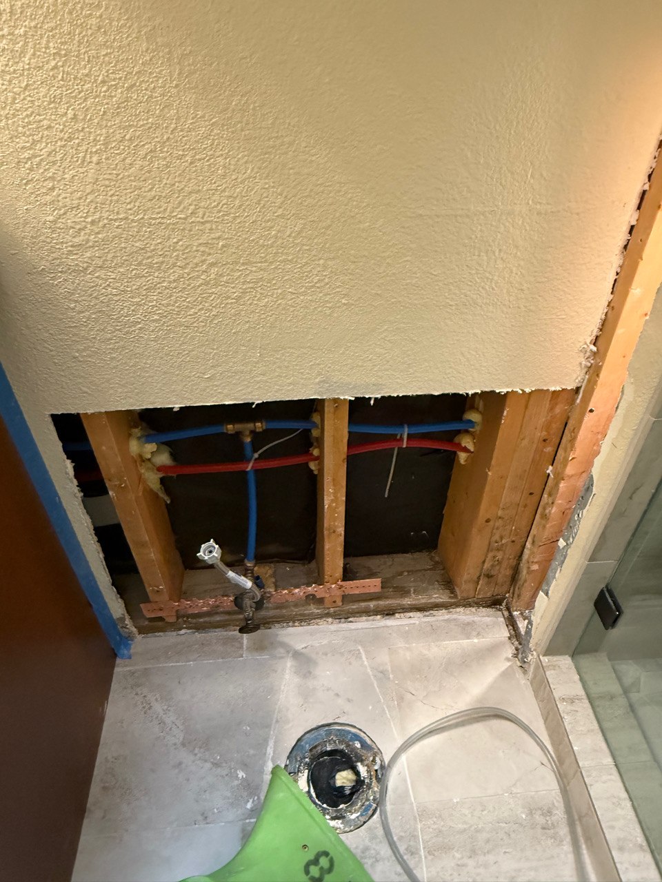 Opened bathroom wall exposing framing and plumbing in a Sun City Anthem home