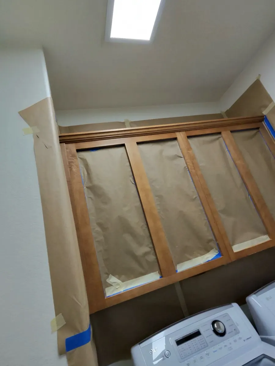 Before: laundry room cabinets masked with paper and tape in an Anthem home