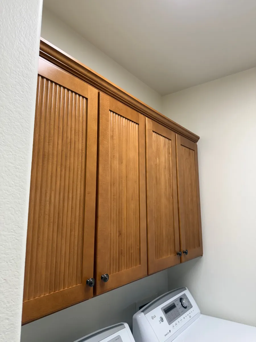 After: refinished wood laundry room cabinets above the washer in an Anthem home