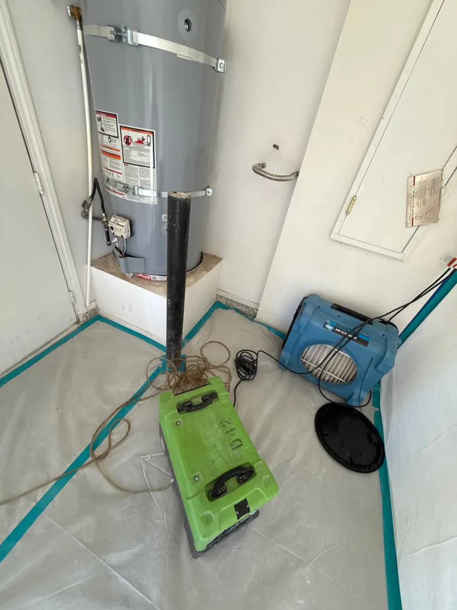 Dehumidifier and air scrubber inside plastic containment by a water heater in a Centennial Hills garage
