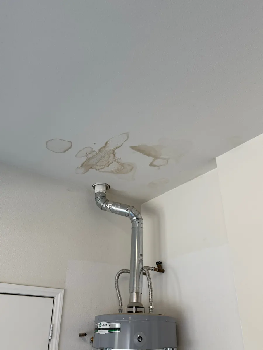 Before: brown water stains on a garage ceiling around a water heater flue in a Centennial Hills home