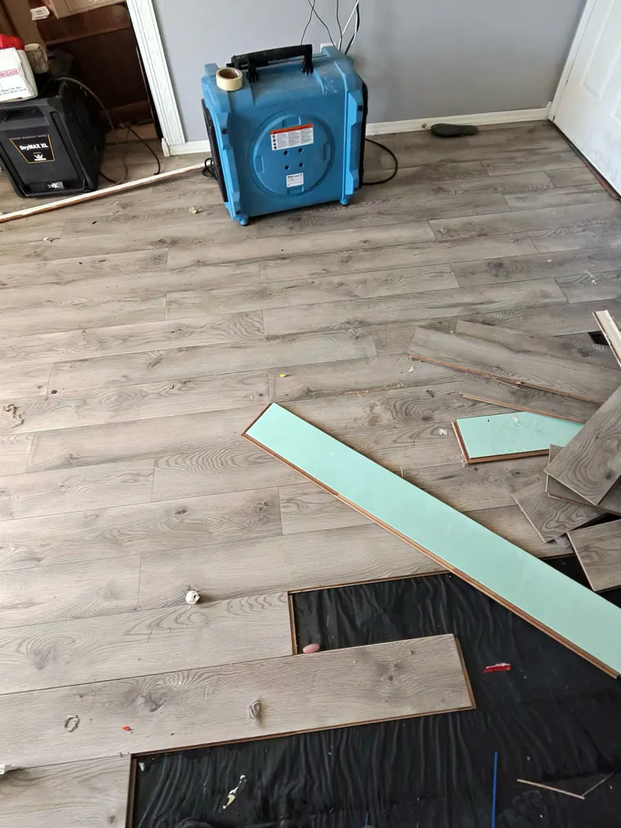 Laminate planks pulled up off black underlayment with a dehumidifier in a Centennial Hills bedroom