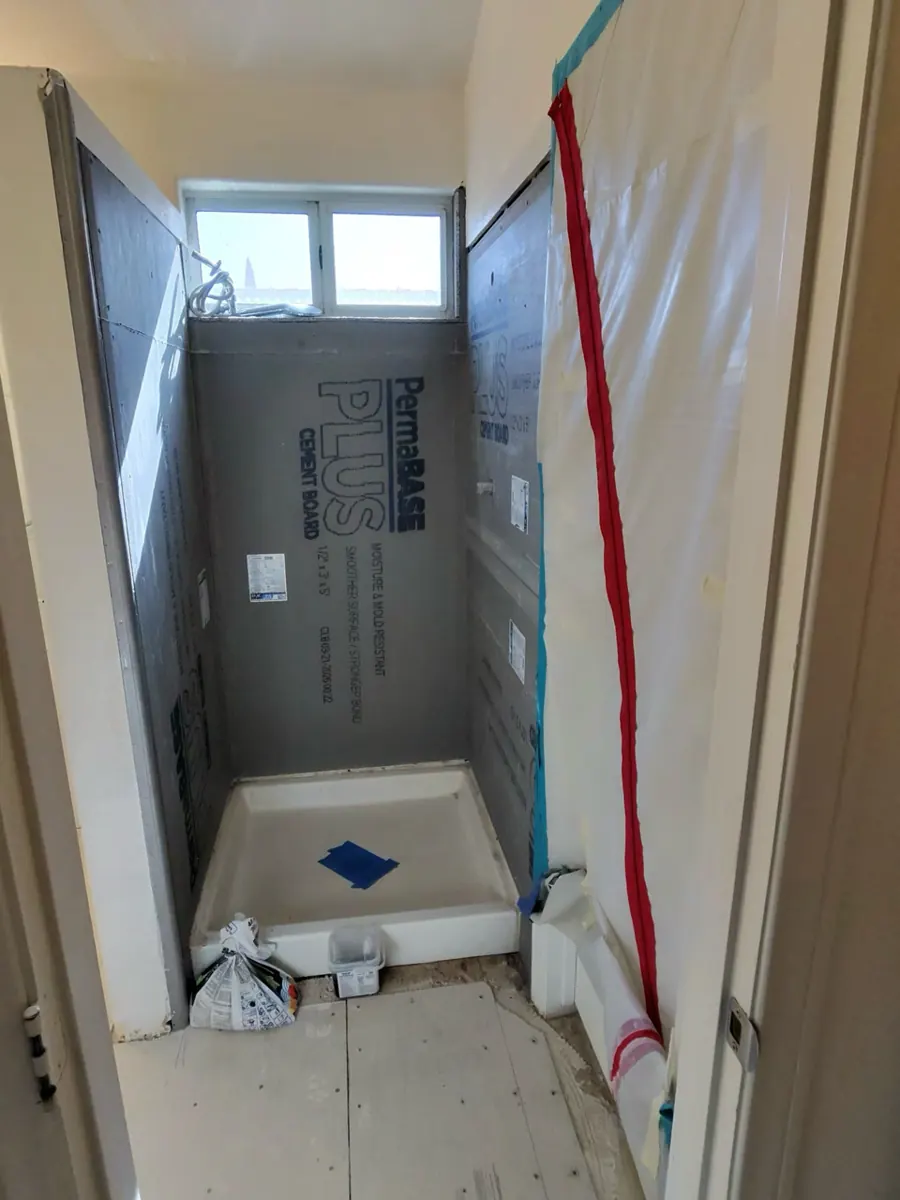 New cement board on the shower walls around a new shower pan in a Desert Shores bathroom