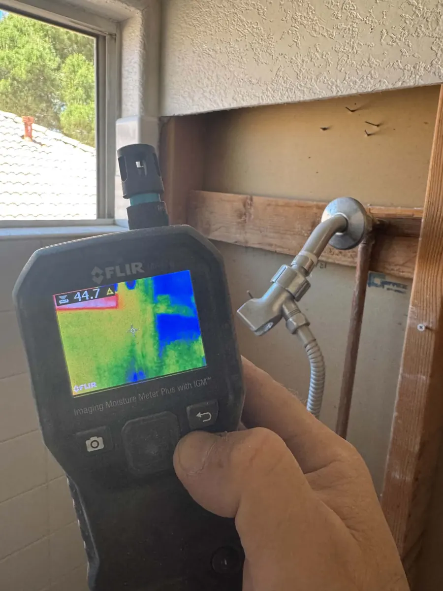 Thermal moisture meter held at an opened shower wall near the valve in a Desert Shores bathroom