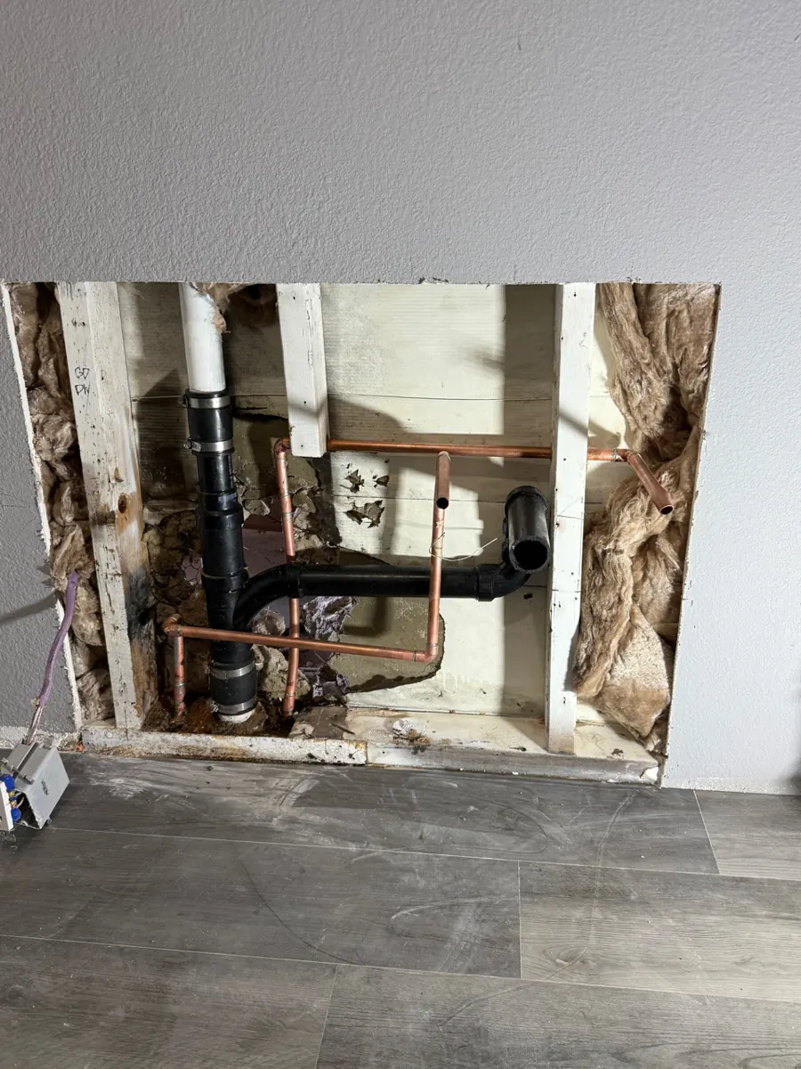 Bathroom wall opened to copper and drain pipes above new flooring in East Las Vegas