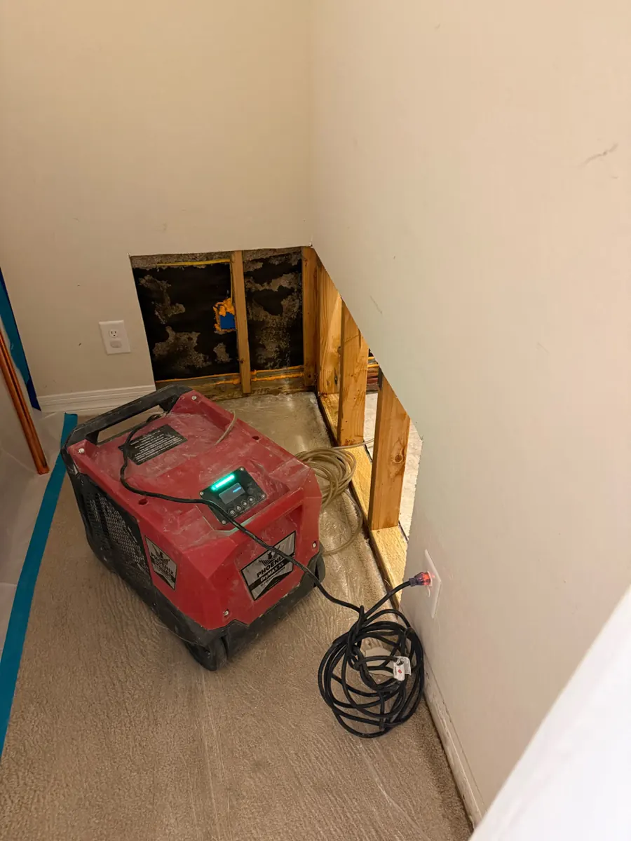 Red dehumidifier running beside an opened lower wall in an Enterprise home