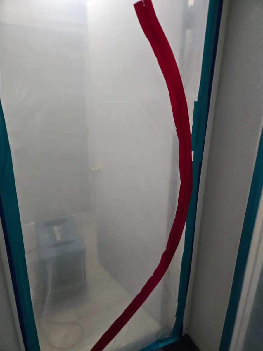 Plastic containment with a red zipper door at a doorway in a Foothills home