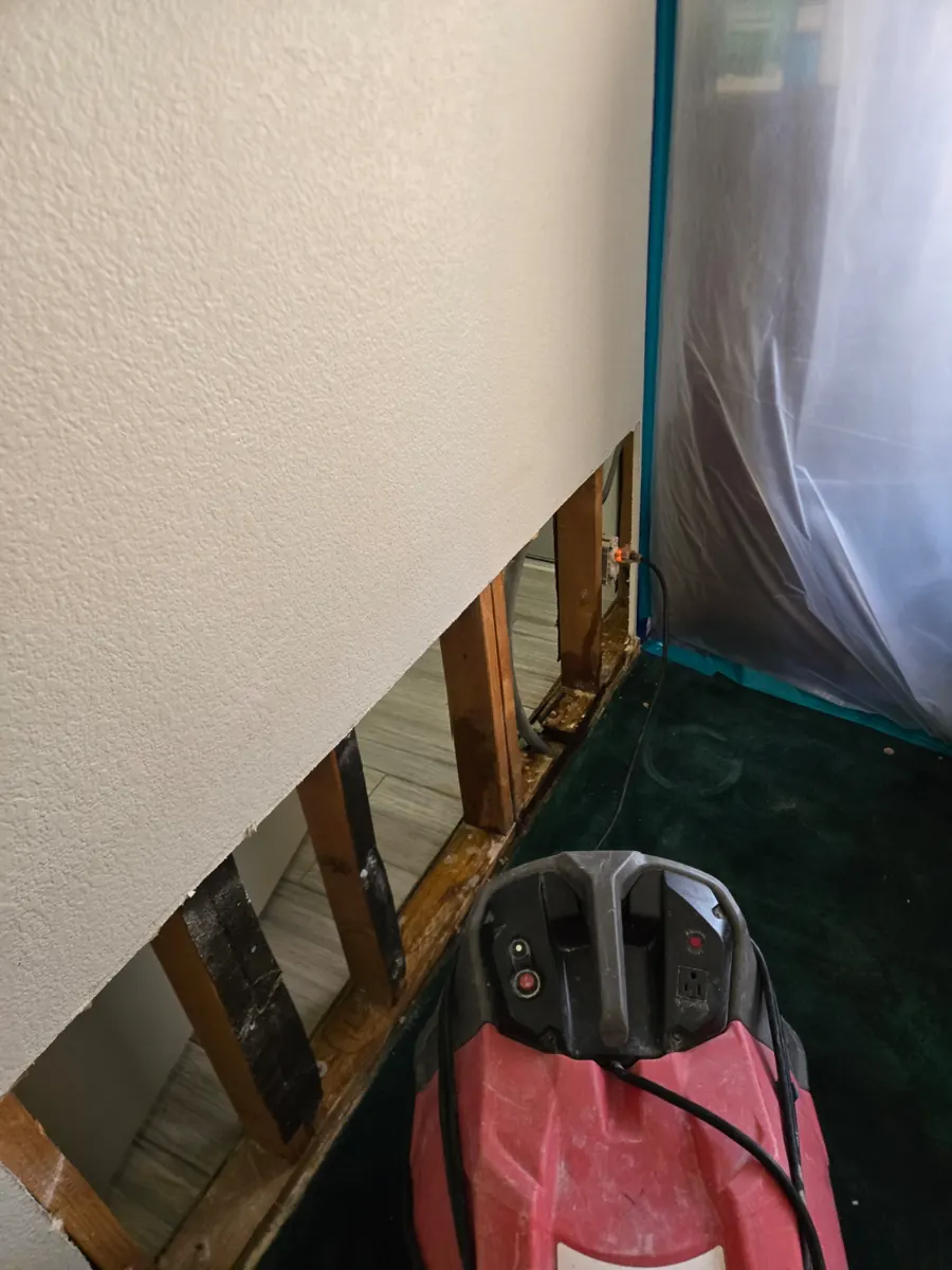 Drying equipment beside an opened wall base and plastic containment in a Foothills home