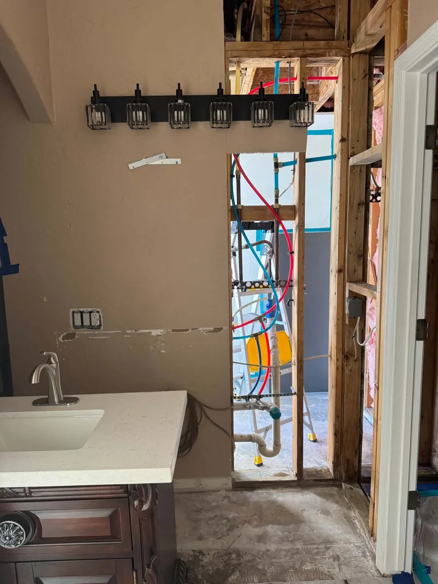 Bathroom wall opened to the studs and supply lines beside the vanity in a Lake Havasu City home