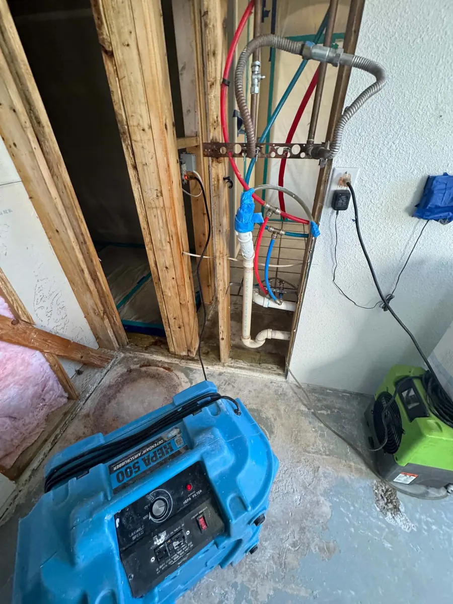 Garage plumbing wall opened to the framing with a dehumidifier in a Lake Havasu City home