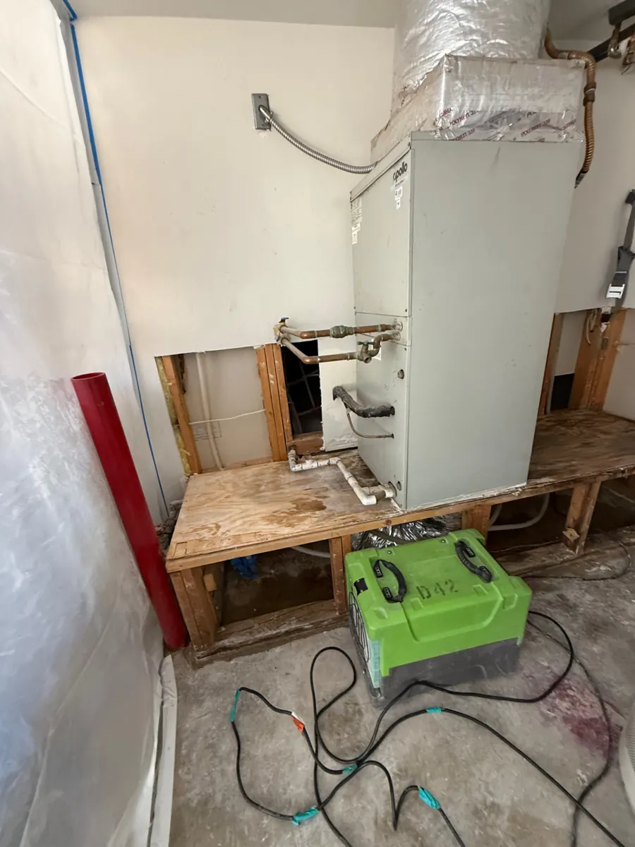 Before: furnace platform with drywall cut out and a dehumidifier running in a Lone Mountain garage