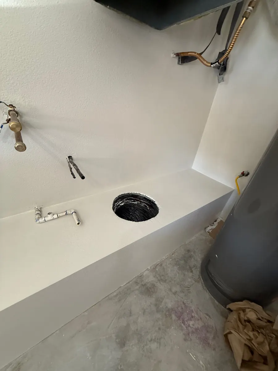 After: water heater platform and walls rebuilt with new drywall and texture in a Lone Mountain garage