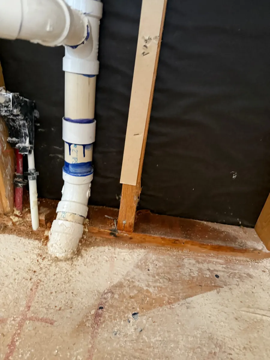 Bathroom wall opened to the drain line and framing in a Sunridge Heights home