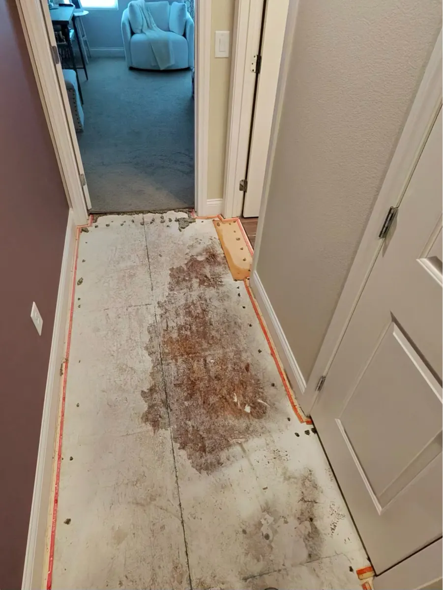 Hallway carpet and pad removed to show a stained subfloor in a McCullough Hills townhome
