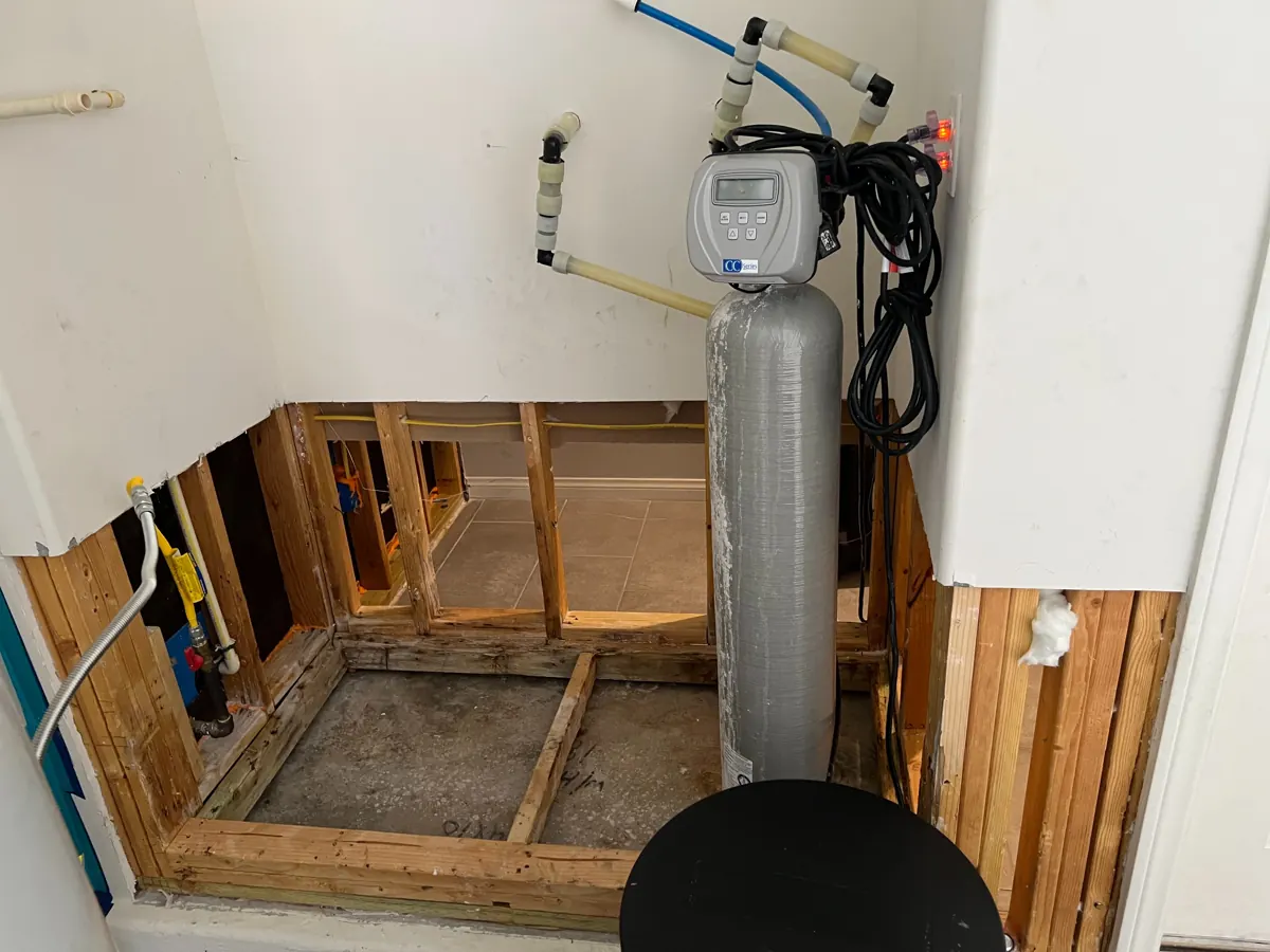 Lower walls cut open to the studs around a water softener alcove in a McCullough Hills home