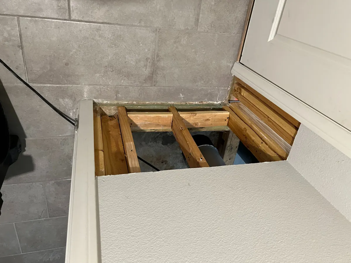 Drywall removed from the base of a wall beside a tiled floor in a McCullough Hills home