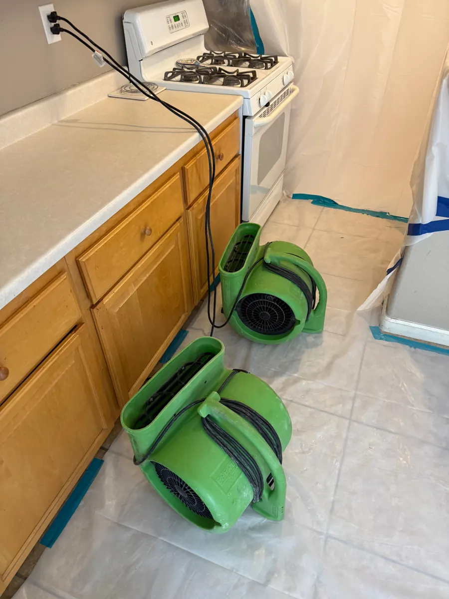 Two air movers on a plastic-covered kitchen floor in a North Las Vegas home
