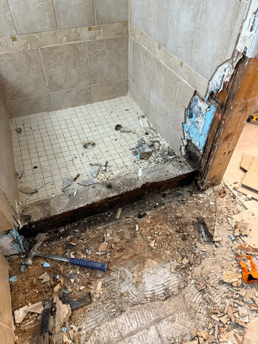 Shower curb and wall corner opened with tile debris on the floor in a Northwest Las Vegas bathroom