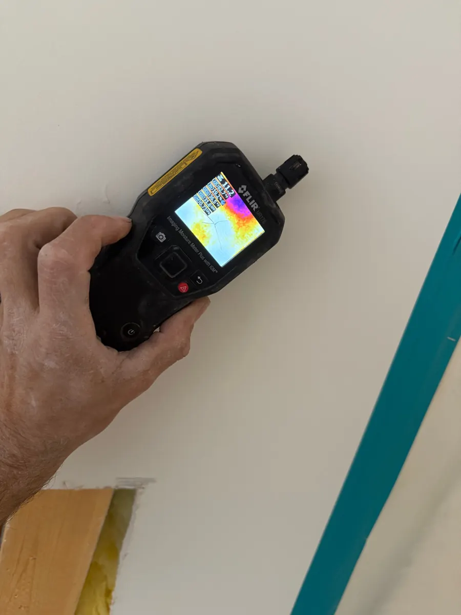 Thermal moisture meter held to a ceiling inside a taped containment in Paradise Hills