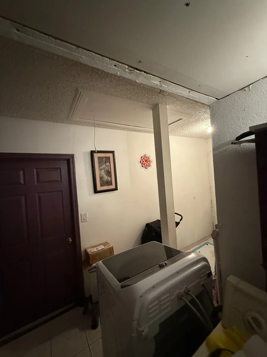 Ceiling drywall pulled down above the washer in a Paradise laundry room