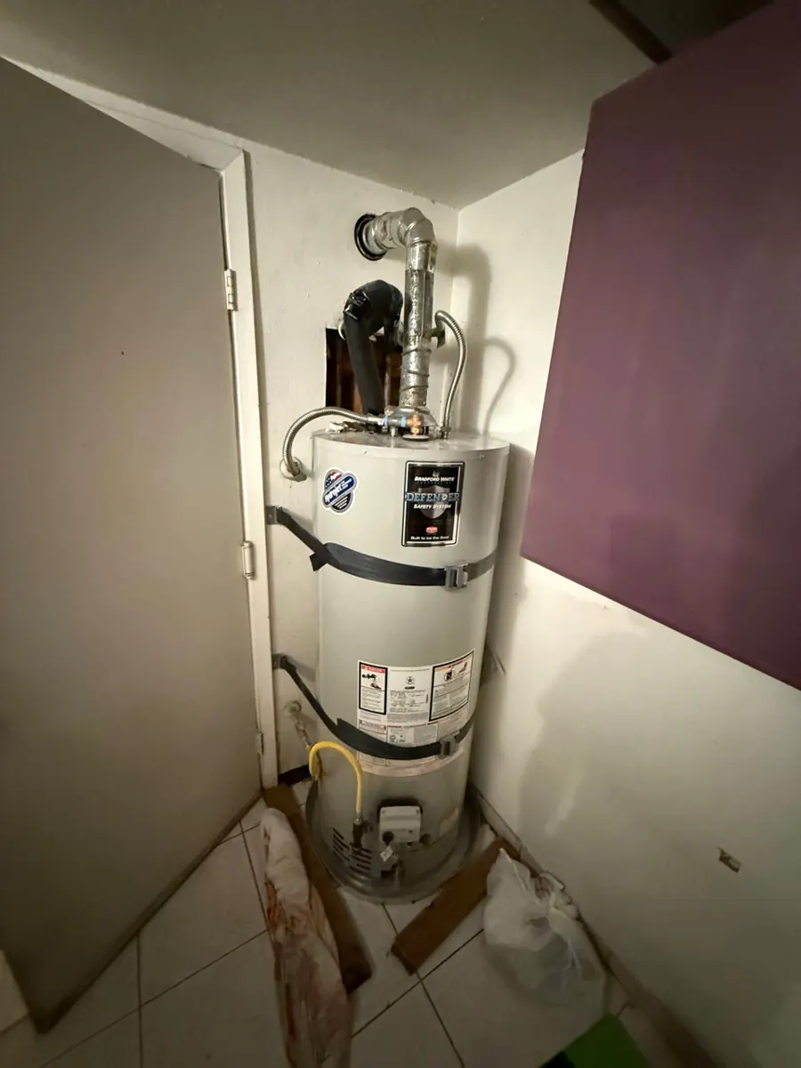 Wall opened behind a water heater in a closet in a Paradise home