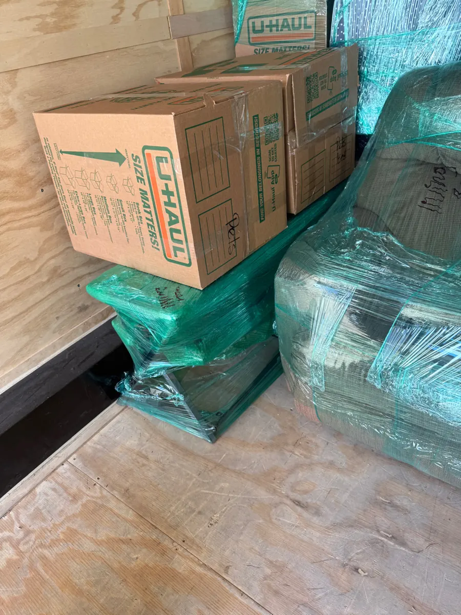 Labeled moving boxes stacked on shrink-wrapped furniture during a Pittman pack-out