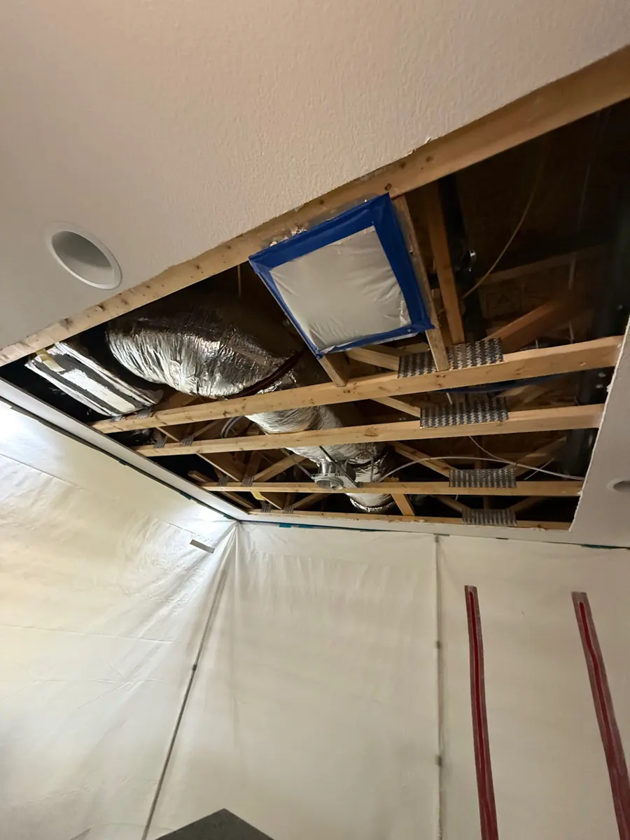 Kitchen ceiling opened to the joists above plastic containment walls in a Providence home