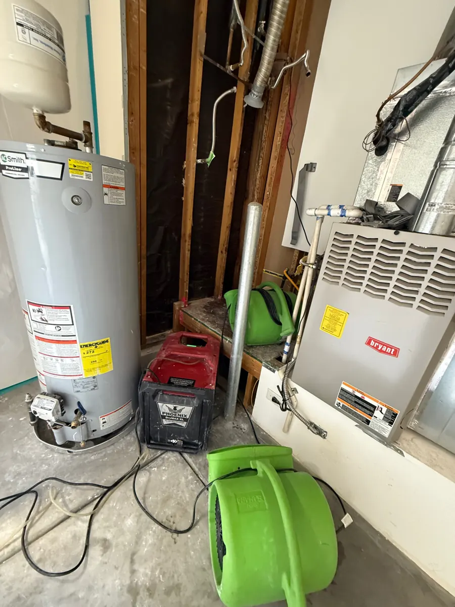 Air mover and dehumidifier beside a water heater in an opened garage closet near Providence