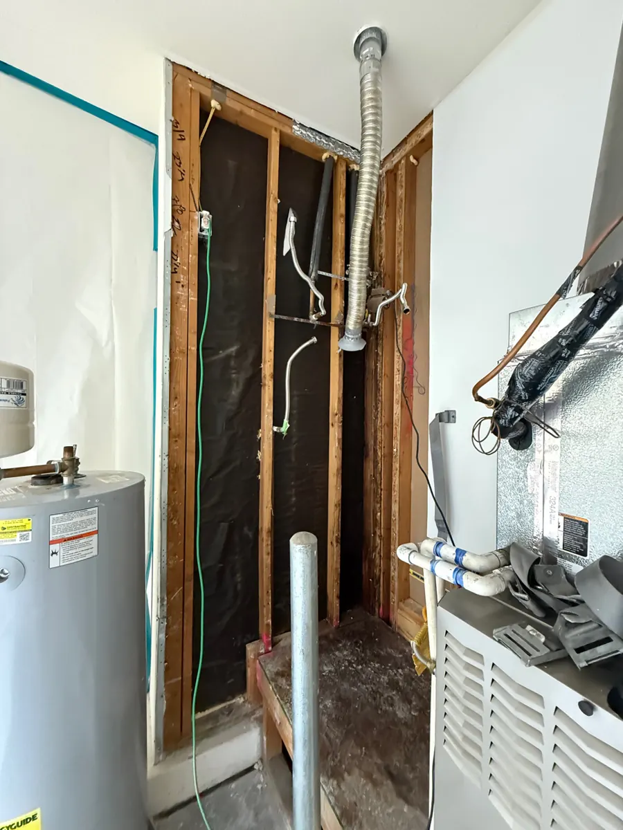 Garage utility closet wall opened to the studs beside a water heater near Providence