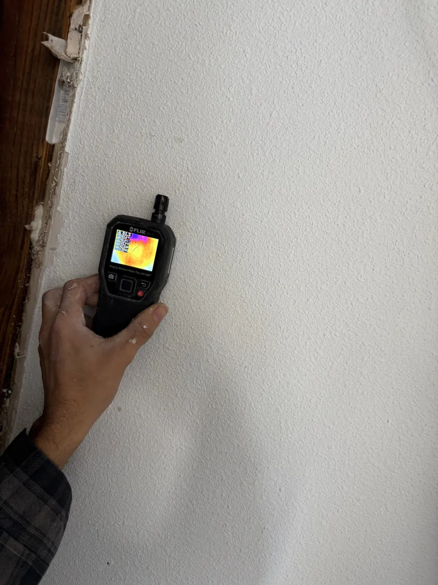Thermal moisture meter held to a garage closet wall near Providence