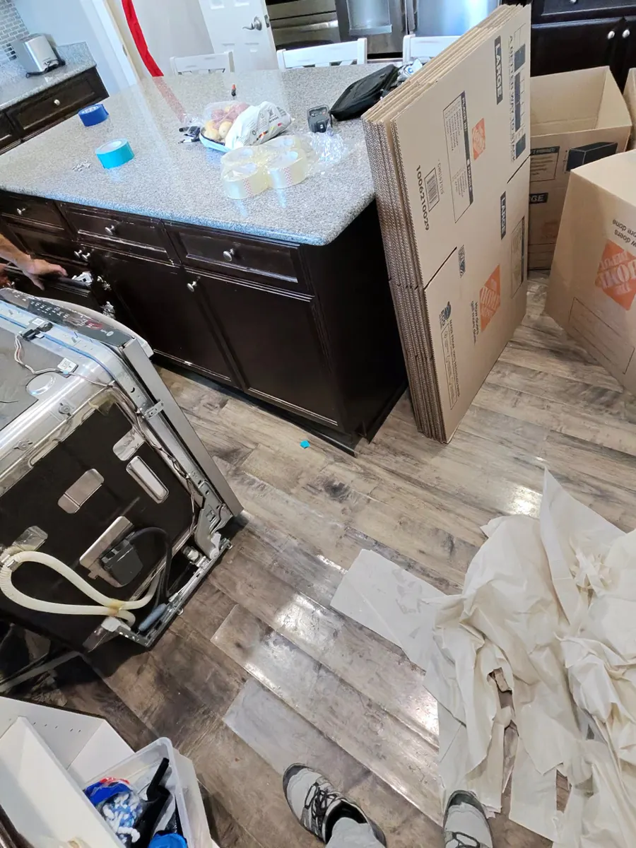 Dishwasher pulled out beside the kitchen island with moving boxes ready in a Providence home