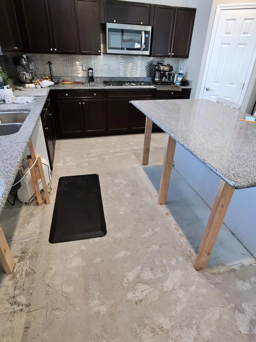 Granite island top on temporary wood legs over a bare kitchen slab in a Providence home