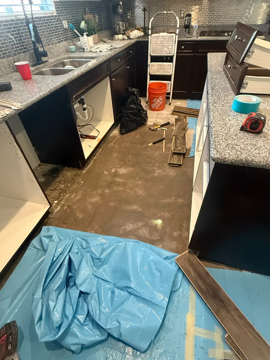 Kitchen with plank flooring pulled up and cabinets opened in a Providence home