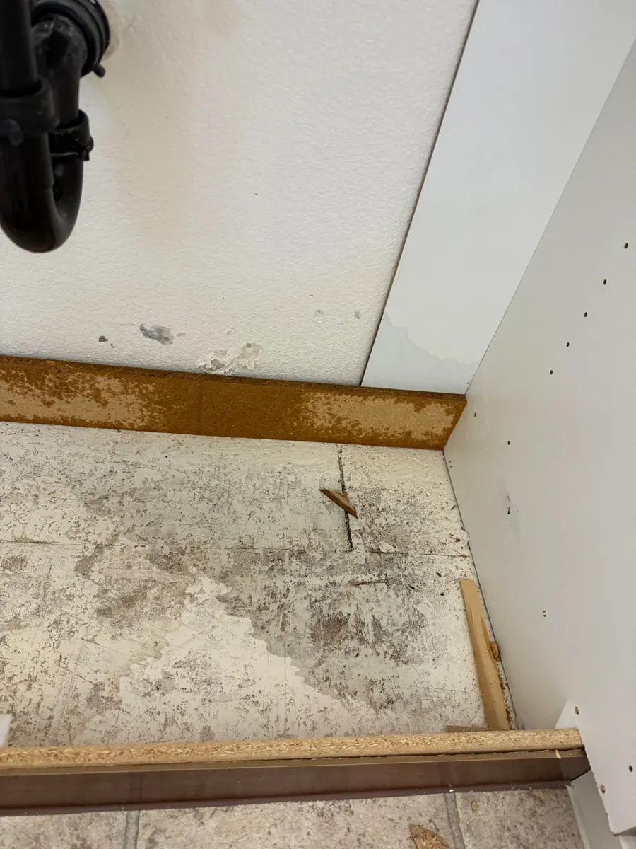 Bathroom vanity cabinet bottom removed to expose a stained subfloor in a Providence home