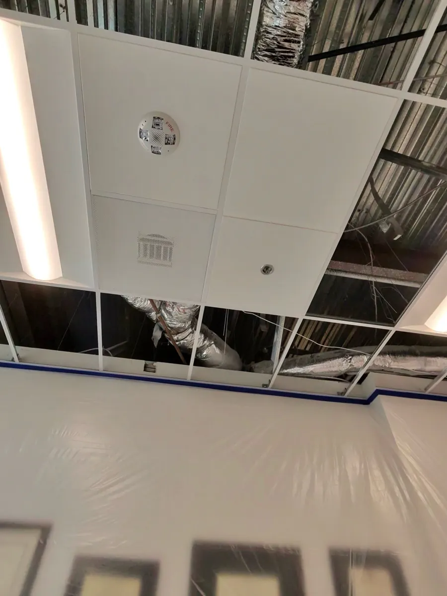 Ceiling grid opened to ductwork above plastic-covered walls in an office suite near Queensridge