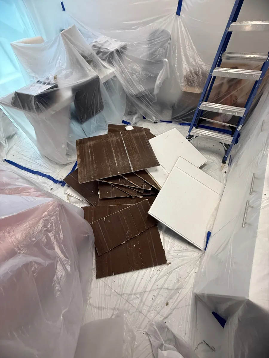 Stained and white ceiling tiles stacked on plastic in a covered office near Queensridge
