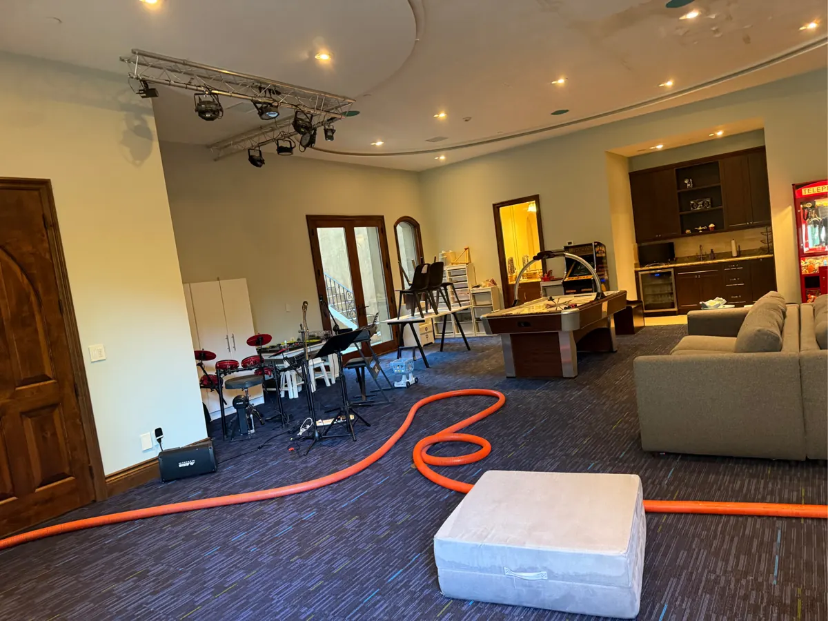 Game room with marks and peeling on the ceiling and an equipment hose on the carpet in a Red Rock Country Club home