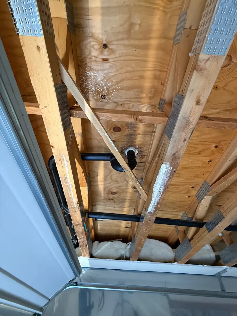 Garage ceiling opened to roof framing and drain lines in a River Mountain home