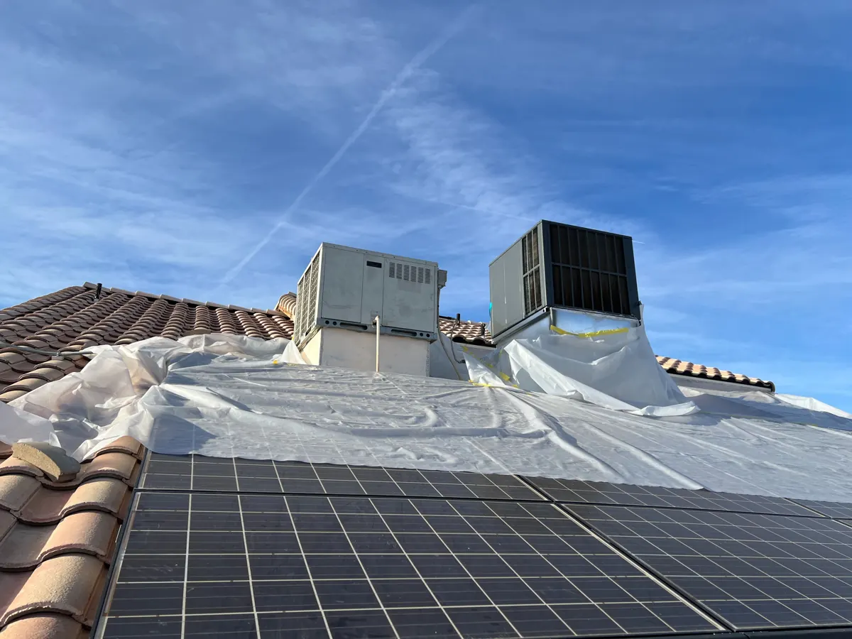 Plastic sheeting over a tile roof section beside rooftop AC units in River Mountain