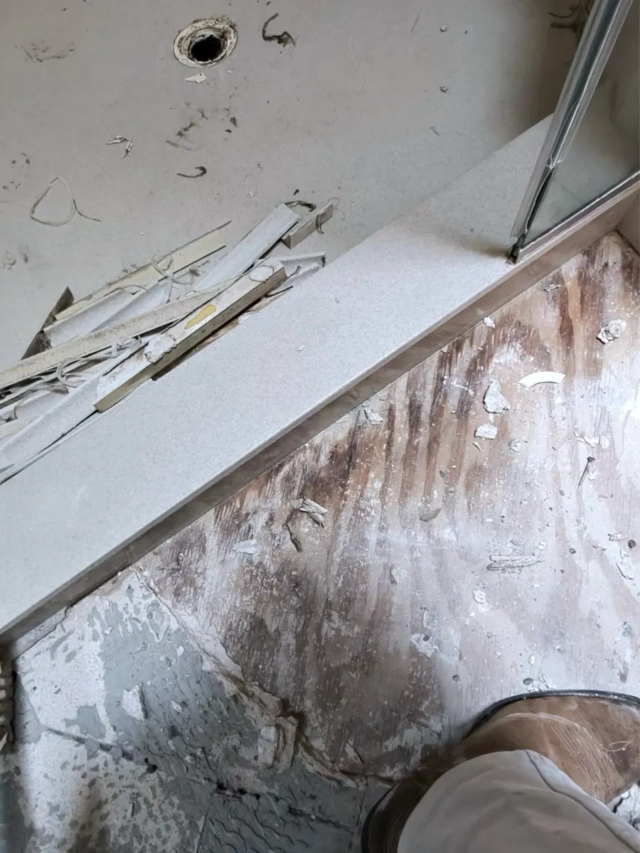 Shower floor covering removed to show a stained subfloor in a River Mountain bathroom