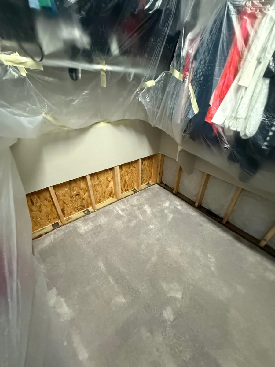 Walk-in closet with lower walls cut out and clothes wrapped in plastic in a Skye Canyon home