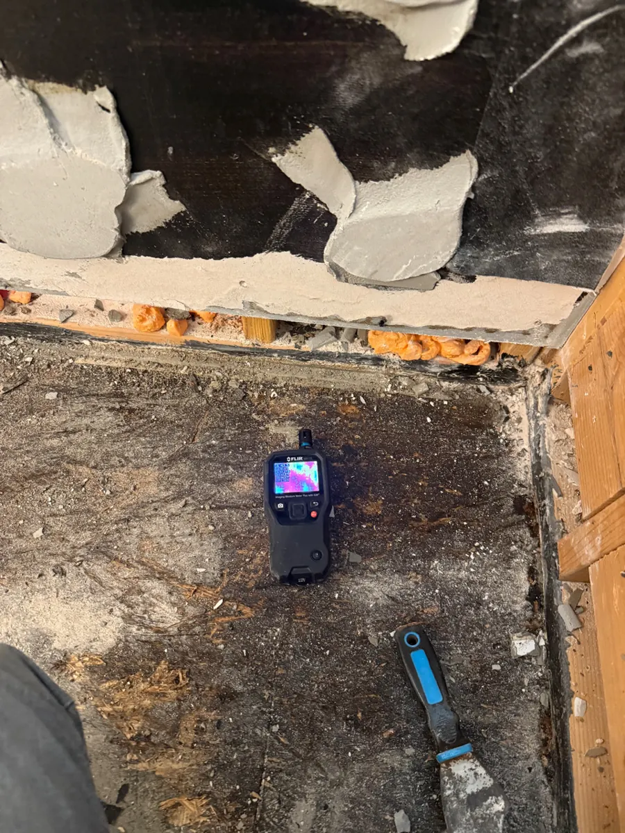 Thermal moisture meter on dark stained subfloor after shower pan removal in Southern Highlands