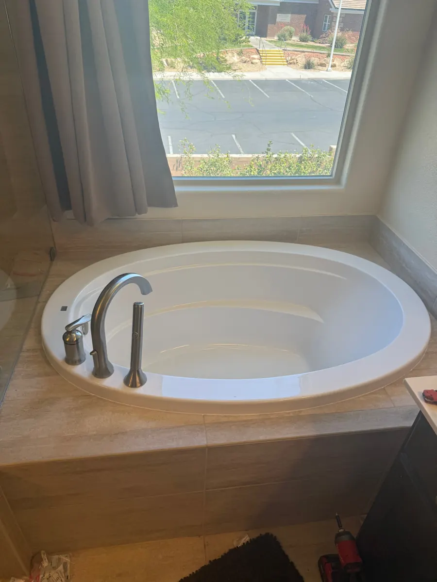 New oval soaking tub set in a tiled deck under a window in a West Henderson bathroom