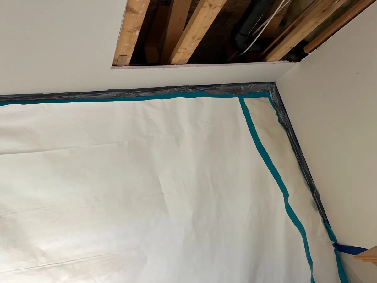 Ceiling opened to joists above a taped plastic containment wall in West Sahara