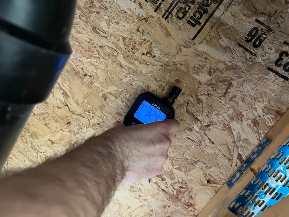 Moisture meter held on the subfloor above an opened ceiling in a West Sahara home