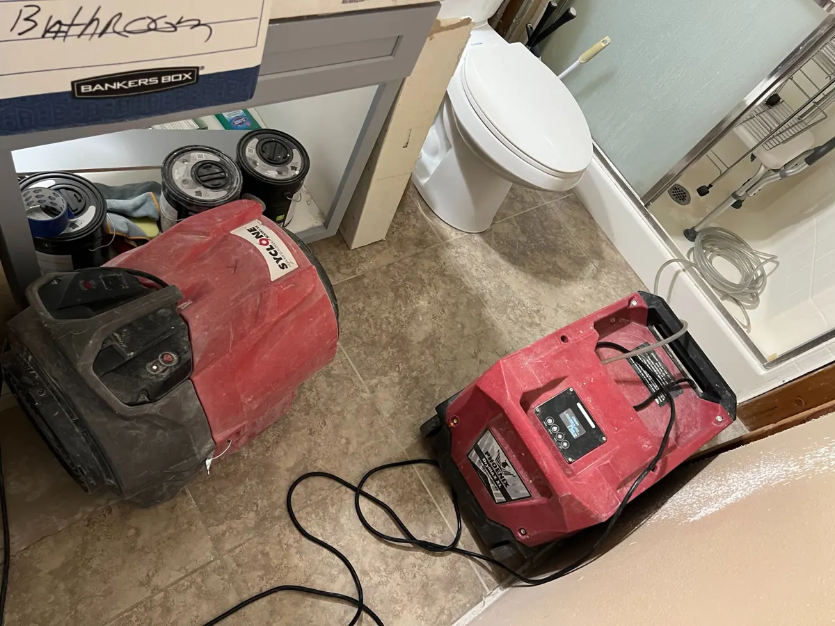 Dehumidifier and air mover on a tile bathroom floor in a Whitney home