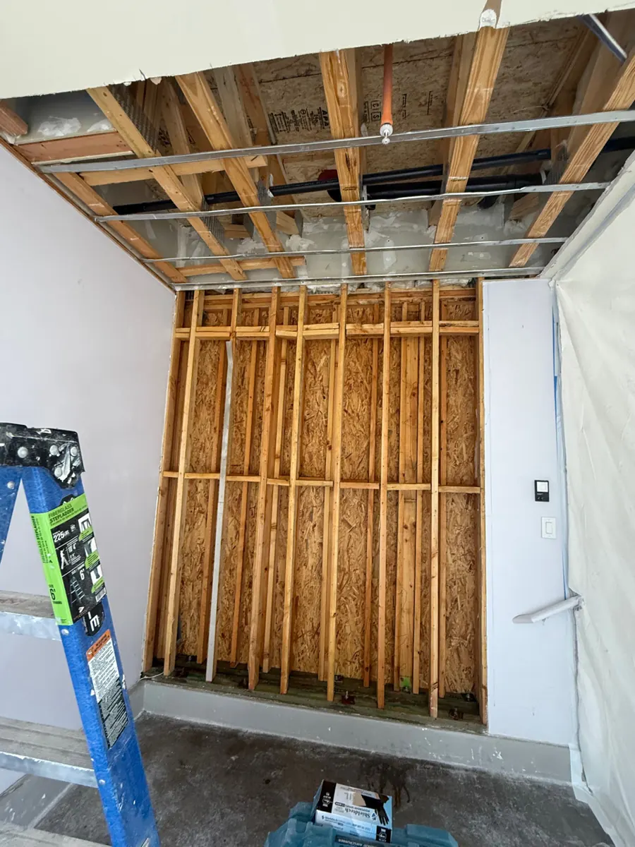 Garage wall stripped to studs and ceiling opened to joists in a Whitney home