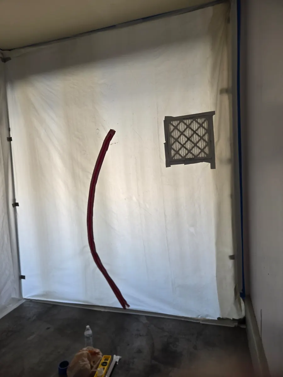 Plastic containment wall with a filter panel set up in a Whitney garage
