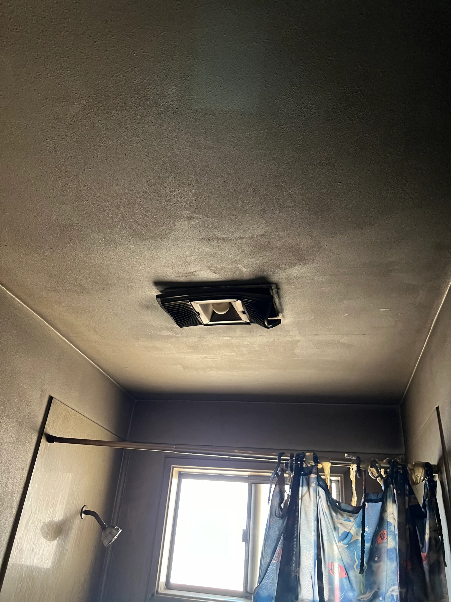 Bathroom ceiling and walls stained by smoke and soot after a fire